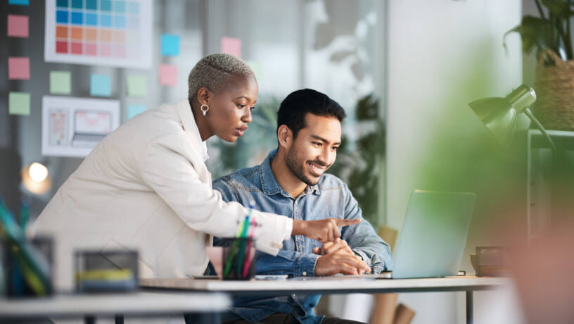 two marketing employees working on laptop together