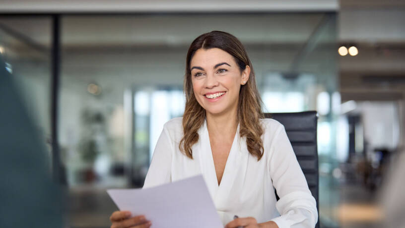 Woman smiling while handling papers at a desk